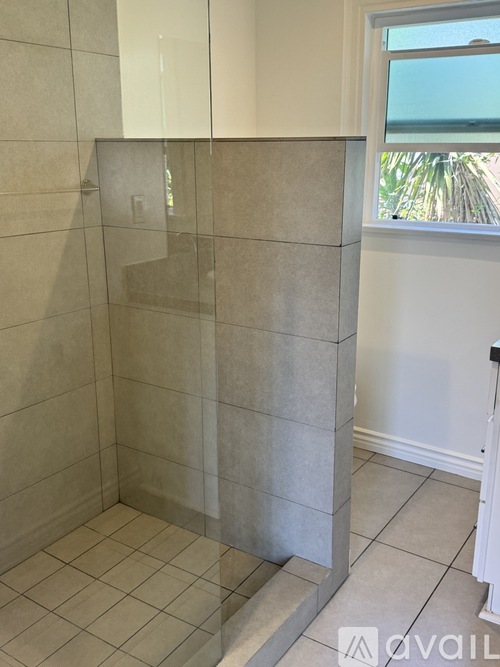 A bathroom with a glass shower door and tiled floor.