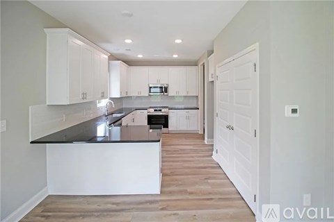 A kitchen with white cabinets and a black countertop.