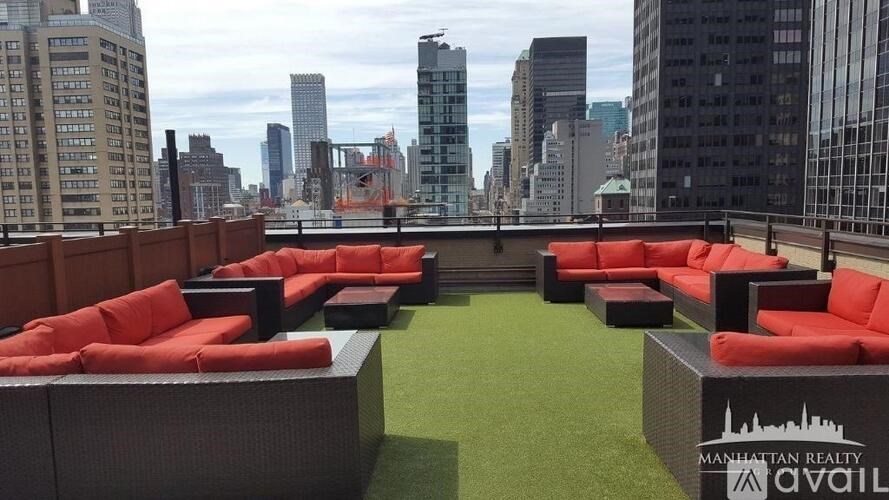 A rooftop patio with red couches and a city skyline in the background.