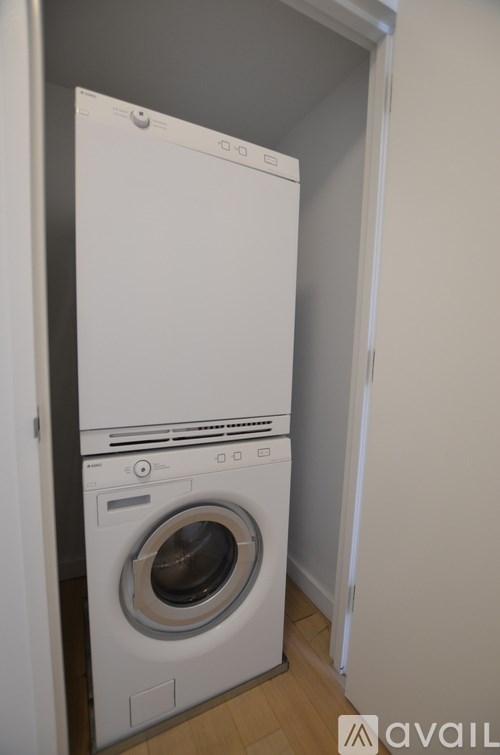 A white dryer and washer are stacked on top of each other in a small room.