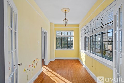 A hallway with yellow walls and a wooden floor.