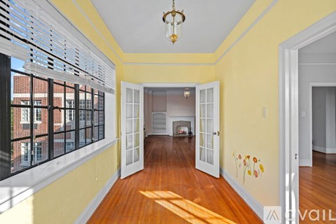 A yellow hallway with a chandelier and a doorway leading to a living room.
