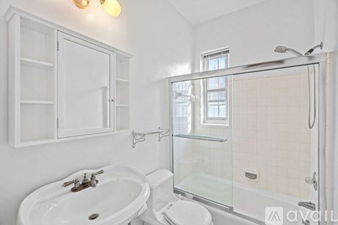 A white bathroom with a glass shower door and a white sink.