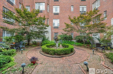 A courtyard with a circular brick design surrounded by brick buildings.