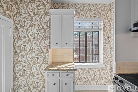 A kitchen with a window and a wallpapered wall.