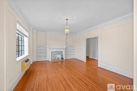 A large, empty room with wood flooring and a fireplace.