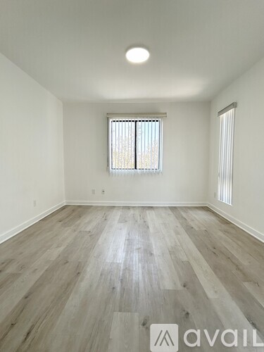 A room with wooden flooring and a window with blinds.