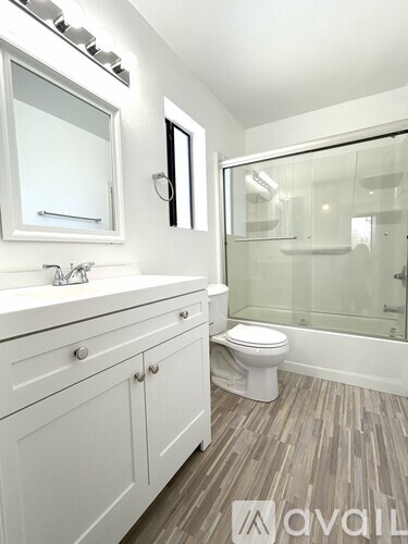 A white bathroom with a toilet, sink, and mirror.