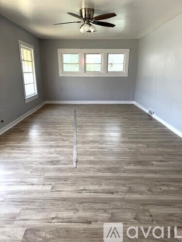 A room with wooden flooring and a ceiling fan.