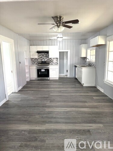 A spacious kitchen with a fan and wooden flooring.