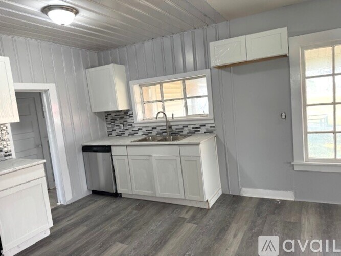 A kitchen with white cabinets and a wooden floor.