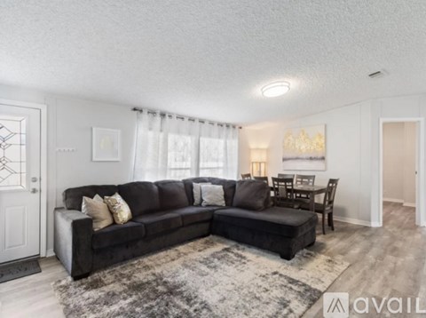 A living room with a black couch and a rug.