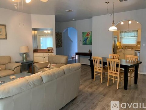 A living room with a white couch and wooden chairs.