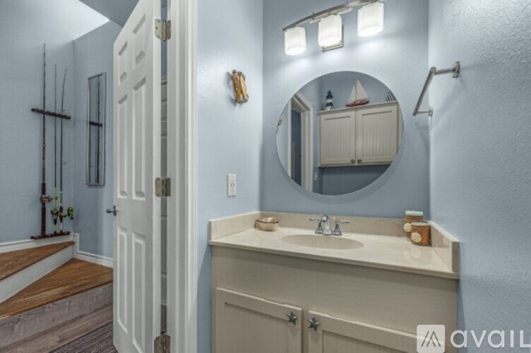 A bathroom with a sink, mirror, and lighting fixtures.