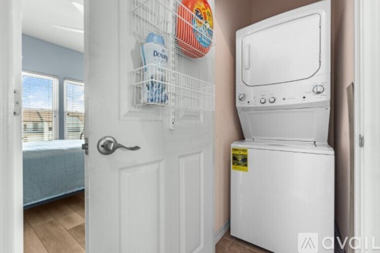 A white toilet is in a small room with a door and a window.