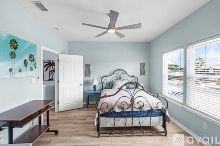 A bedroom with a bed, a table, and a ceiling fan.