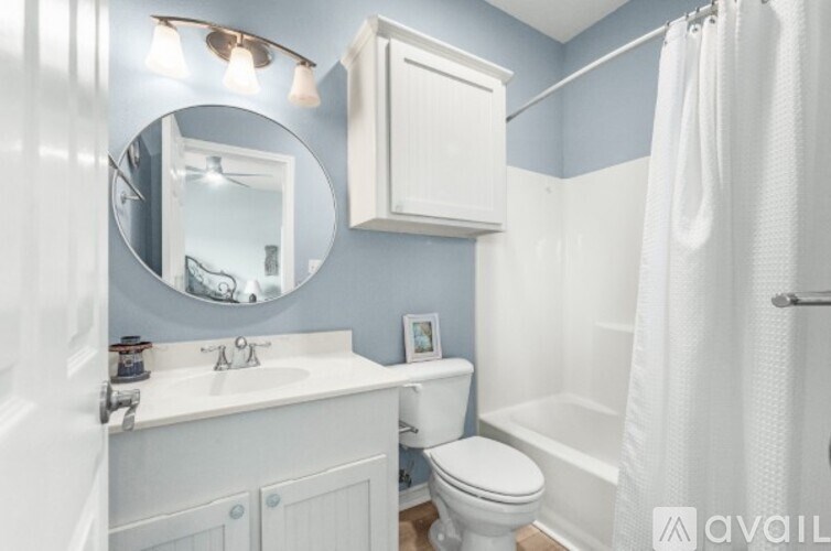 A bathroom with a white toilet, sink, and shower curtain.