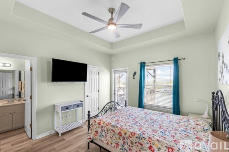 A bedroom with a floral bedspread and a ceiling fan.