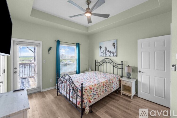A bedroom with a bed, a ceiling fan, and a view of the water.