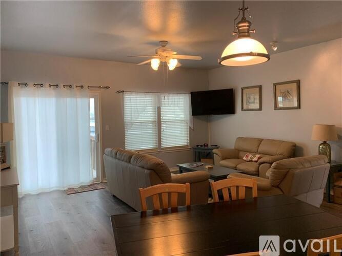 A living room with a couch, chairs, and a television.