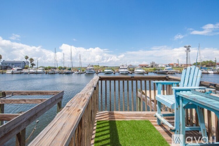 A wooden deck with a blue chair and a table overlooking a marina.