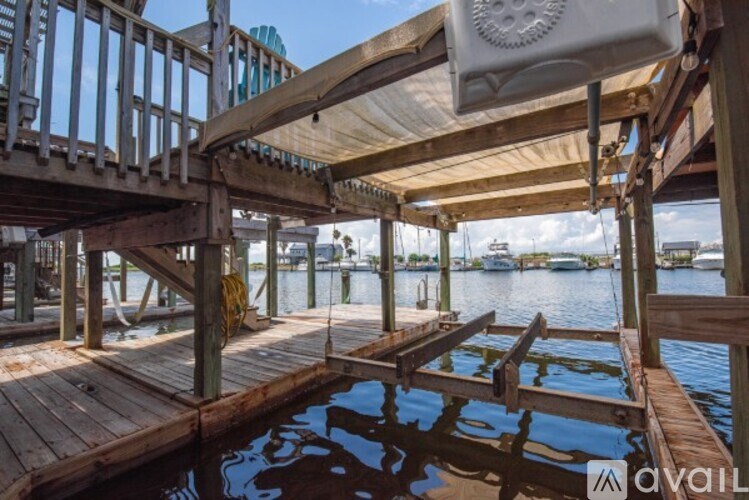 A wooden dock with a white canopy and a boat in the background.
