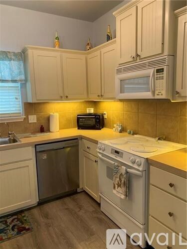 A kitchen with white cabinets and appliances.