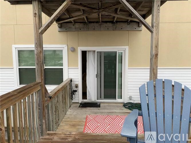 A wooden deck with a blue chair and a red and white rug.