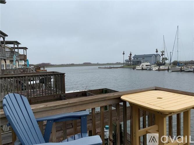 A wooden deck with a blue chair and a table overlooking a body of water.
