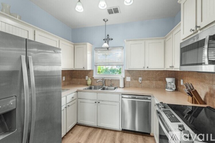 A kitchen with a stainless steel refrigerator and a black stove top.