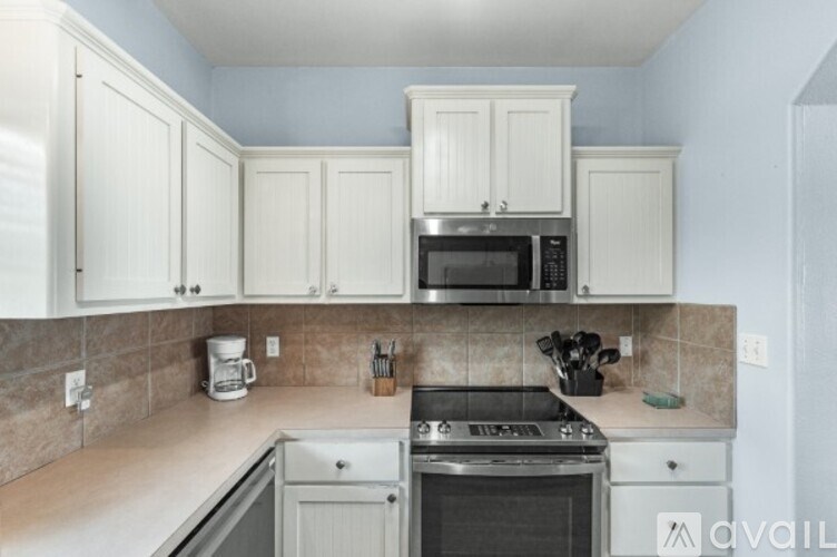 A kitchen with white cabinets and a microwave above the stove.