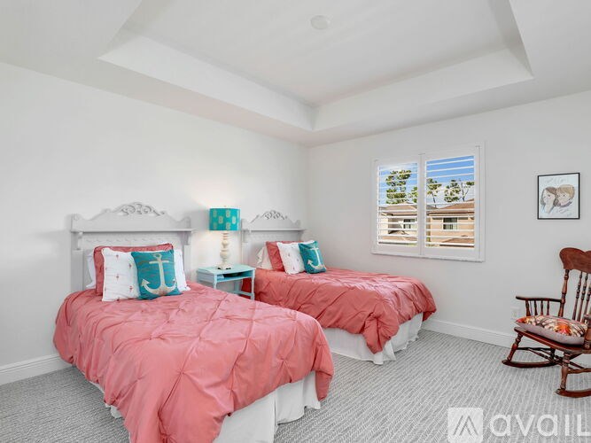 A bedroom with two beds and a rocking chair.