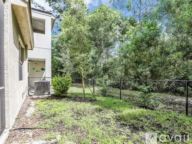 A house with a fenced yard and trees in the background.