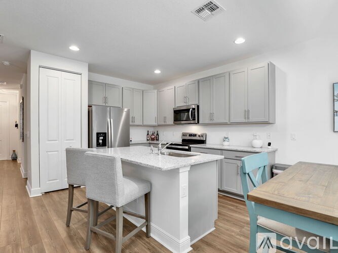 A kitchen with a white island and a wooden table.