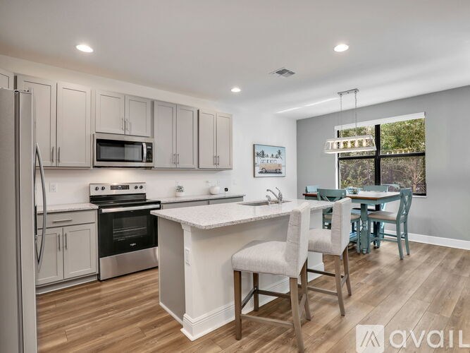 A kitchen with a white island and wooden floors.