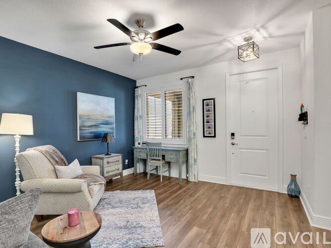 A living room with a ceiling fan and a painting on the wall.