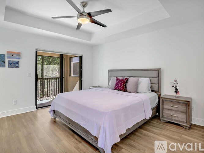 A bedroom with a bed, nightstand, and sliding glass doors.