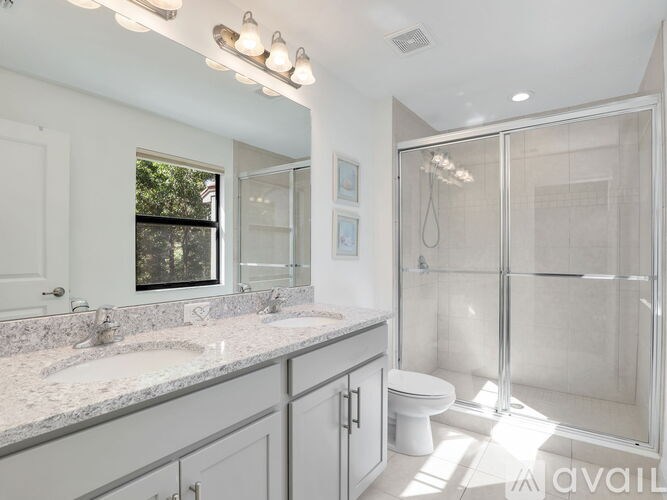 A bathroom with a glass shower stall and a toilet.