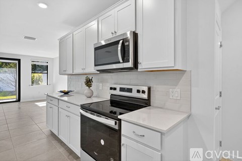 A modern kitchen with white cabinets and appliances.