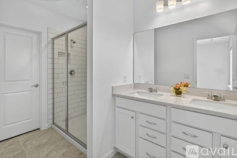 A bathroom with a white vanity, a mirror, and a glass shower door.