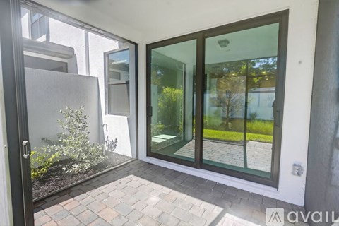 A patio area with a glass door and a brick floor.