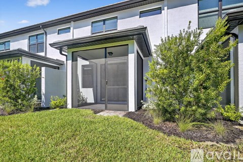 A modern house with a glass door entrance and a well-manicured lawn.