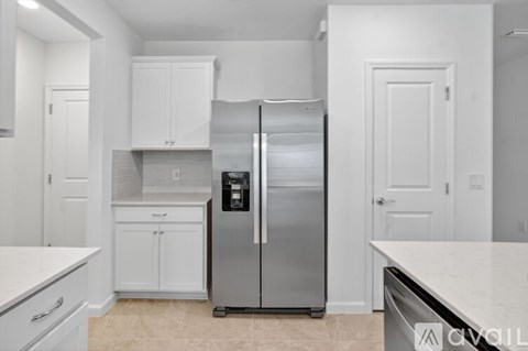 A kitchen with a stainless steel refrigerator and white cabinets.