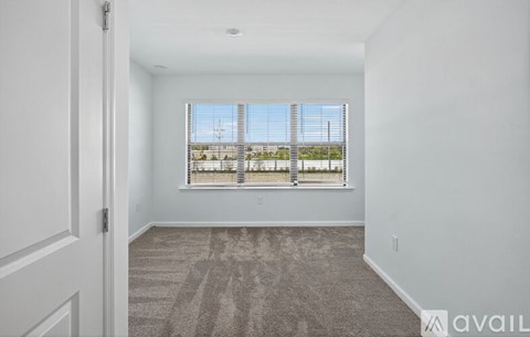 A room with a carpeted floor and a window with blinds.