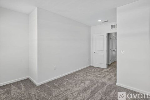 A room with a carpeted floor and a door leading to another room.