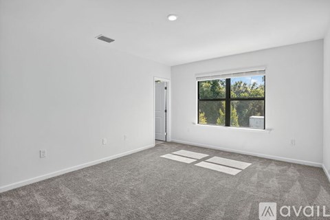 A spacious room with a large window and a carpeted floor.