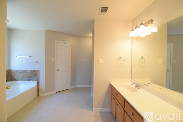 A bathroom with a tub, sink, and mirror.