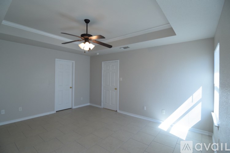 A room with a ceiling fan and two doors.