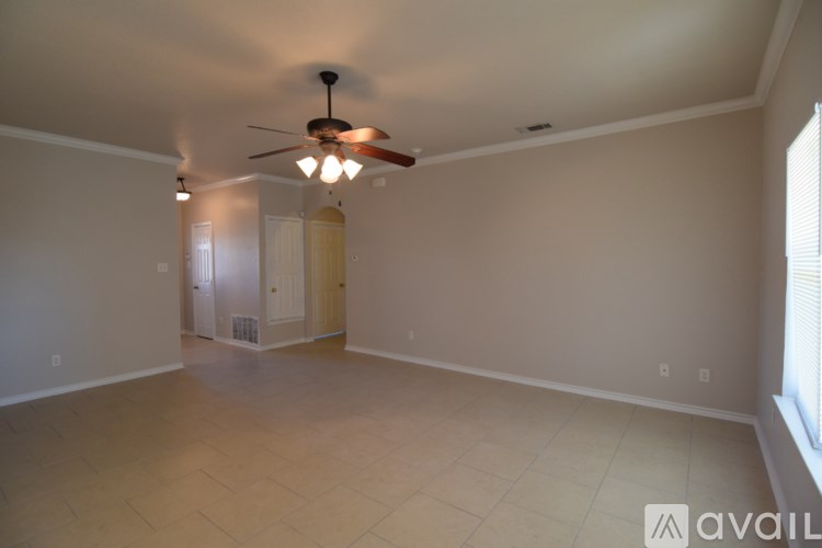 A room with a ceiling fan and a door in the background.