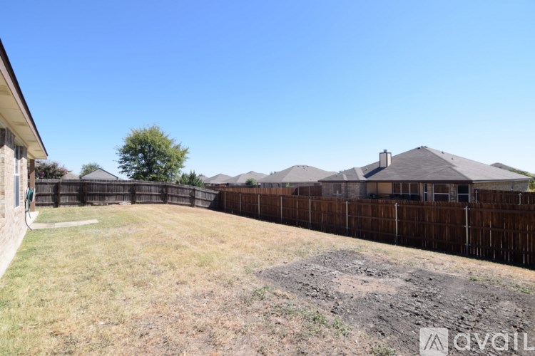 A backyard with a fence and a house in the background.